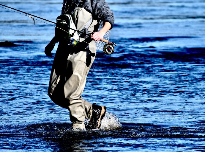 man in black jacket and brown pants fishing on sea during daytime