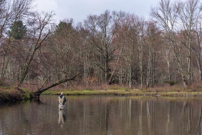 person in white jacket and black pants standing on river during daytime